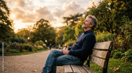 Relaxed man sitting on park bench at sunset