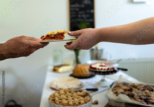 Cutting homemade lattice fruit pie at authentic dessert buffet table during casual celebration highlighting baking tradition and lifestyle culture