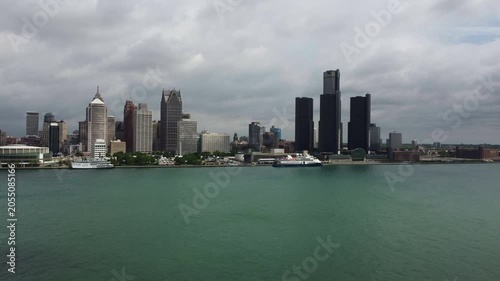Detroit, Michigan on a hazy mixed sunshine and clouds spring day circa May, 2022. Shot with a drone over the Detroit River. Moving forward and gaining altitude.
