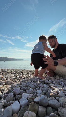 Father and toddler on a rocky beach by the sea