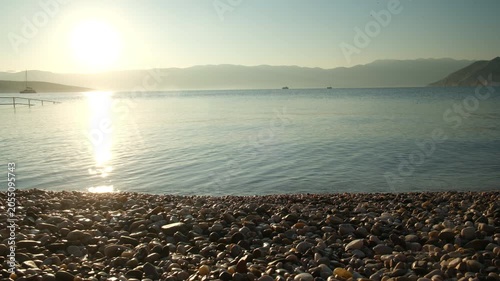Calm lake sunrise with rocky shore and mountains