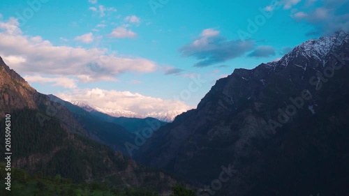 Wide angle shot of scenic mountain valley with snowy Himalayan mountain peaks covered by clouds during evening as seen from Killar town in Chamba district, Himachal Pradesh, India. Natural background