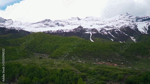 Wide angle shot of snowy Himalayan mountain peaks with clouds above them during the summer season as seen from Sural Bhatori village in Pangi Valley of Chamba district, Himachal Pradesh, India. 