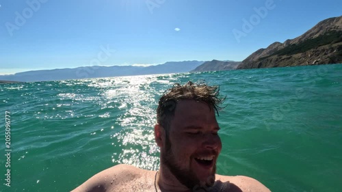 Man taking selfie in turquoise sea by mountains