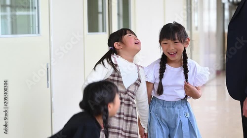学校の廊下で先生を見上げて楽しく会話をする女子小学生たち