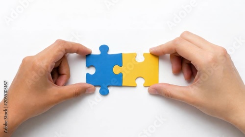 Hands connecting blue and yellow puzzle pieces for teamwork and problem solving