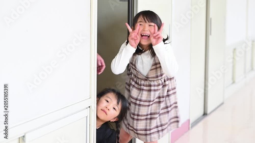 教室のドアから廊下へ笑顔で元気よく飛び出してくる女子小学生たち