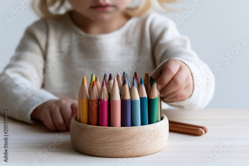 Child choosing colored pencils for school, clean minimal composition.