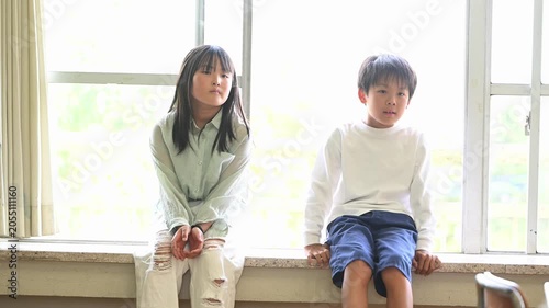 窓際に座って談笑する男女の小学生たち