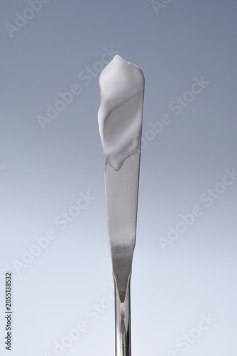 applying sunscreen, cream on a spatula, spf cream swatch, white cream smear, cosmetic textures,  skincare product sample