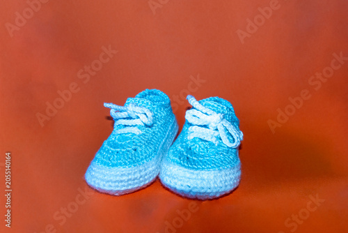 Crocheted baby jacket and booties in beige and white on a blue background, symbolizing warmth and handmade care