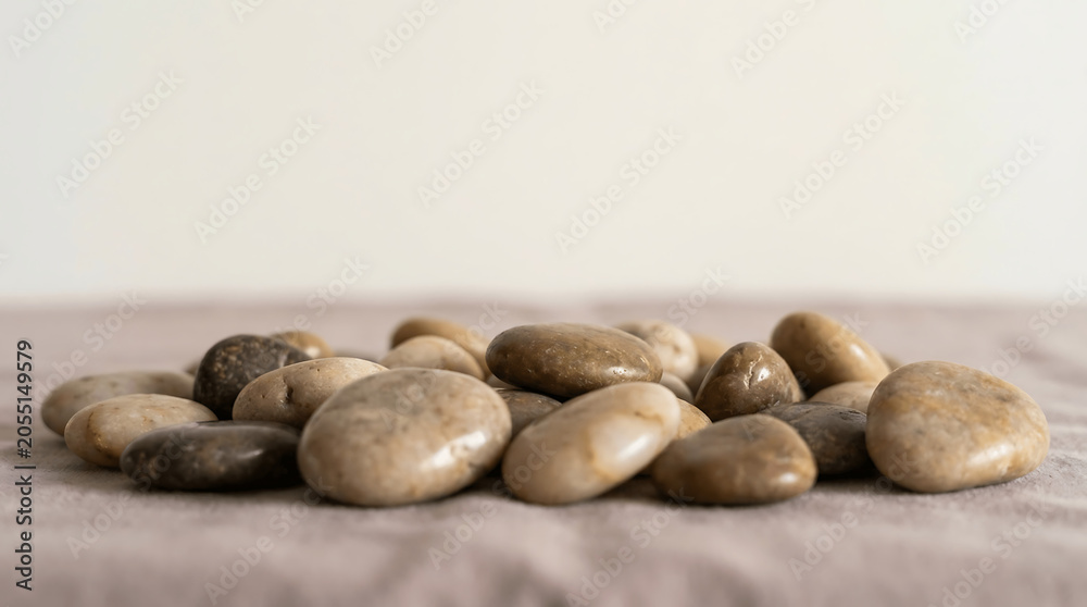 Obraz premium Smooth Polished River Stones Arranged on a Neutral Textured Fabric Surface