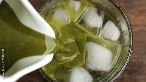 Refreshing Matcha tonic cocktail. Pouring matcha tea in glass with sparkling water and ice cubes