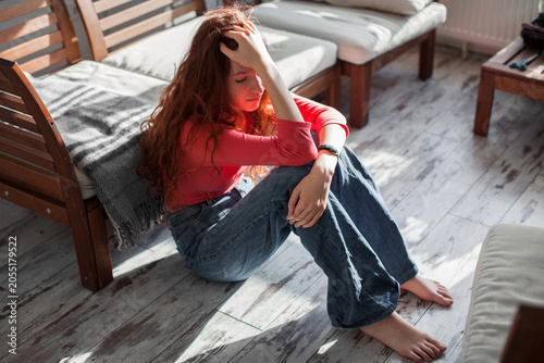 Foto Sad teenage girl sitting on the floor in a room