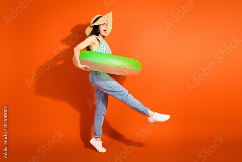 Foto Young stylish woman posing with a green swim ring on bright orange background, e