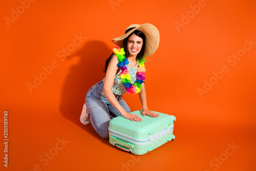 Фотография Young woman in holiday attire posing with a luggage on vibrant orange background