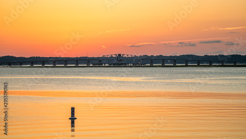 Sunrise view over water near a bridge with reflections on the surface
