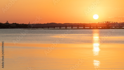 Sunsrise view over the water with bridge in the background and clear sky