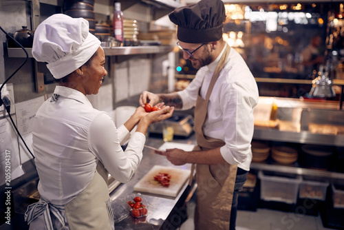 Staff helping chef with tomatoes. Cook in Professional Modern  kitchen  restaurant concept