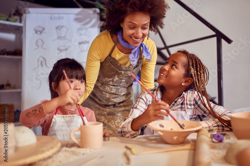 Happy kids and smiling teacher talking while making art with handmade pots. Creative  hobby  activities concept