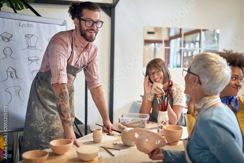 smiling group of people making pots from clay at a pottery studio. Creative, hobby ,activities concept