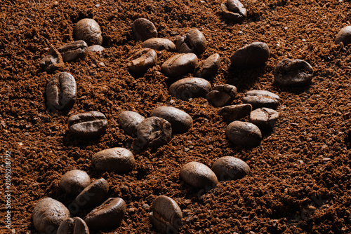 Obraz na płótnie High-Resolution close-up of roasted coffee beans rolling on coarse ground powder