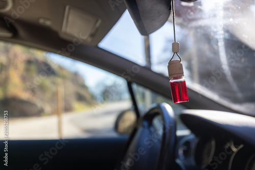 Bild auf Leinwand Red car air freshener hanging from rearview mirror inside vehicle cabin on a sun