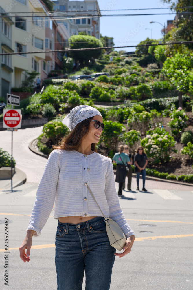 Fototapeta premium Woman walking near the curving flower lined road of Lombard Street in San Francisco