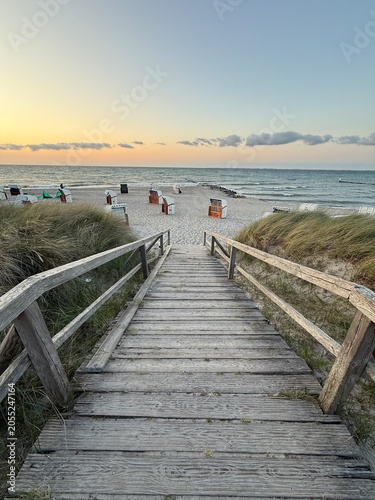 sunset on the beach over wooden path leads to the beach and the sea
