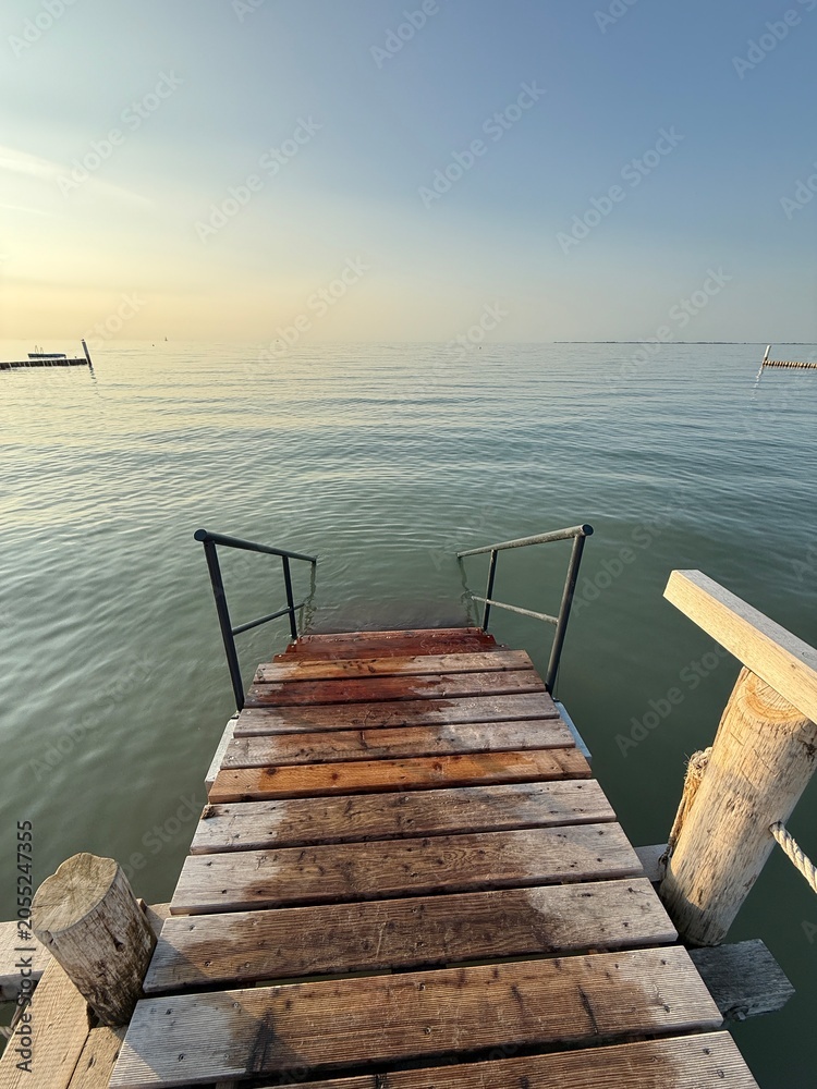 Obraz premium a staircase at the end of the wooden pier leads into the sea