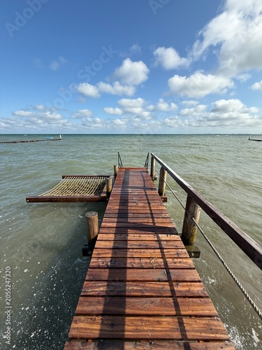 wooden pier on the sea with cozy hammock over the water, summer holiday 