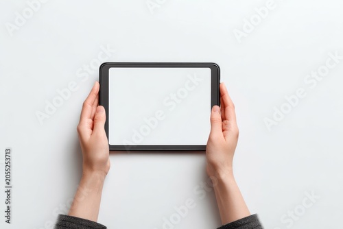 Close-up image shows two hands holding a black rectangular electronic device with a blank white screen against a plain white background
