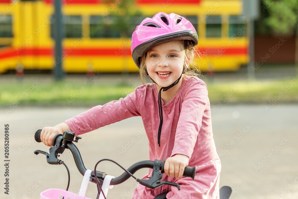 Fototapeta premium Happy child riding bicycle wearing safety helmet outdoors