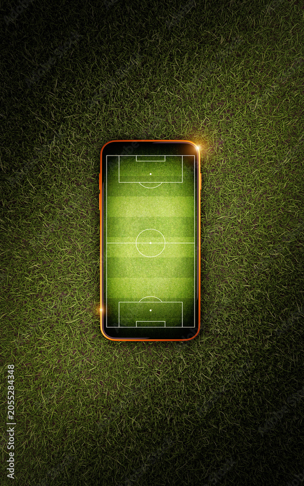 Naklejka premium Mobile phone with soccer field screen on green grass lawn, top view