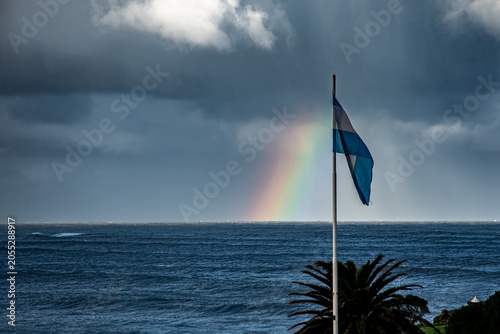 Argentine Flag Over the Ocean with Rainbow and Dramatic Storm Clouds