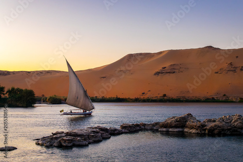Konstfotografi Sand dune and Felucca (traditinal egyptian sailing boat) on the Nile river at su