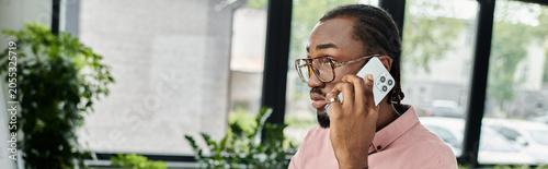 Foto Young african american man engaged in work while talking on the phone indoors