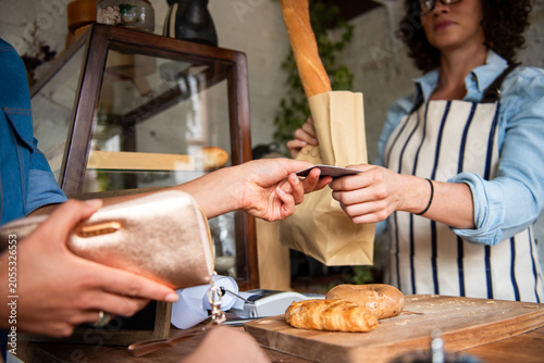 Slika na platnu Customer pays for bread at a bakery counter with a credit card.