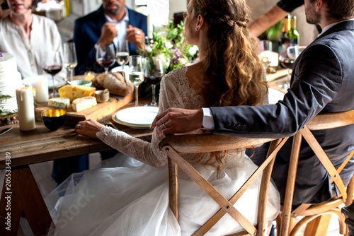 Photos Bride in white dress at a rustic wedding dinner table with guests