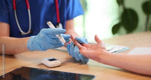 Doctor in gloves uses glucometer to check patient sugar level in blood at appointment. Physician examines woman with diabetes disease in hospital