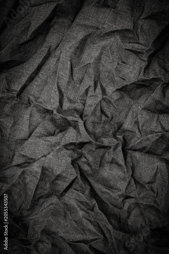 Foto Wrinkled black fabric on a dark surface showing texture and intricate folds in n