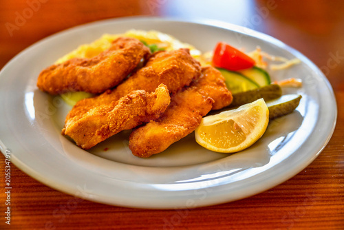 Fried chicken schnitzel with mashed potato and salad on plate.