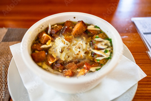 Garlic soup with cheese and fried bred cube in white bowl with napkin and plate.