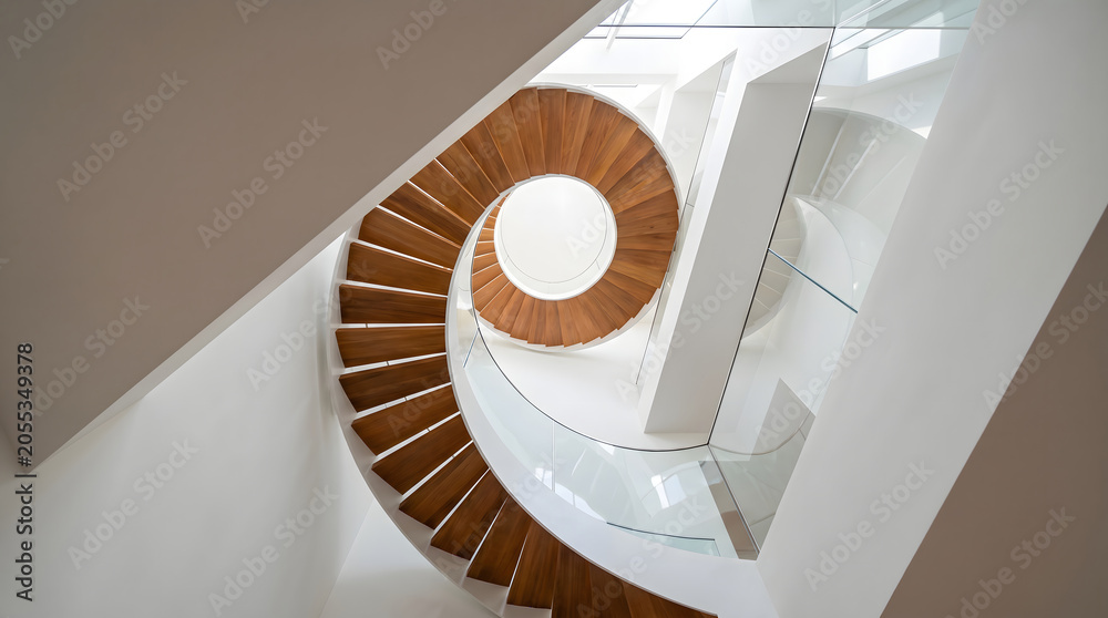 Fototapeta premium Spiral wooden staircase in white interior space captured from overhead perspective