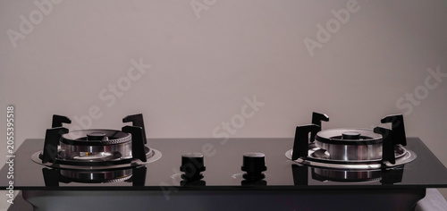 Close-up of a modern gas stove burner on a black glass cooktop. The sleek stainless steel design highlights contemporary kitchen appliances and cooking technology.