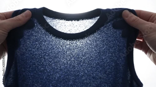 Closeup of a person holding a blue knitted garment against a bright light source