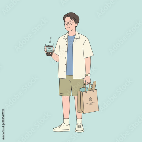 A young man with glasses and casual summer clothes holds a takeaway drink and a shopping bag filled with groceries.