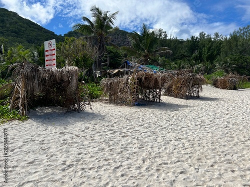 A palm-fringed shelter from the sun on the beautiful Grand Ance Beach on La Digue Island in the Seychelles. Turquoise sea, waves, huge cliffs, white sand