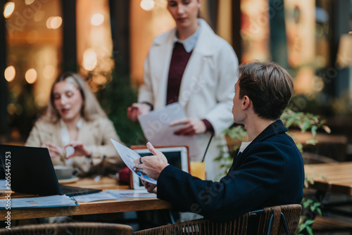 Foto Young professionals review documents and work on a laptop during an outdoor meeting