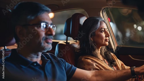 Middle-aged couple driving at night man talking to woman looking out window